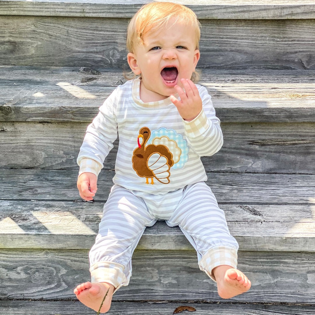 Boys' Mr. Gobble Outfit: A jumper-style garment with white and light grey stripes, showcasing a big turkey on the front. The cuffs are adorned with a light brown checkered pattern.