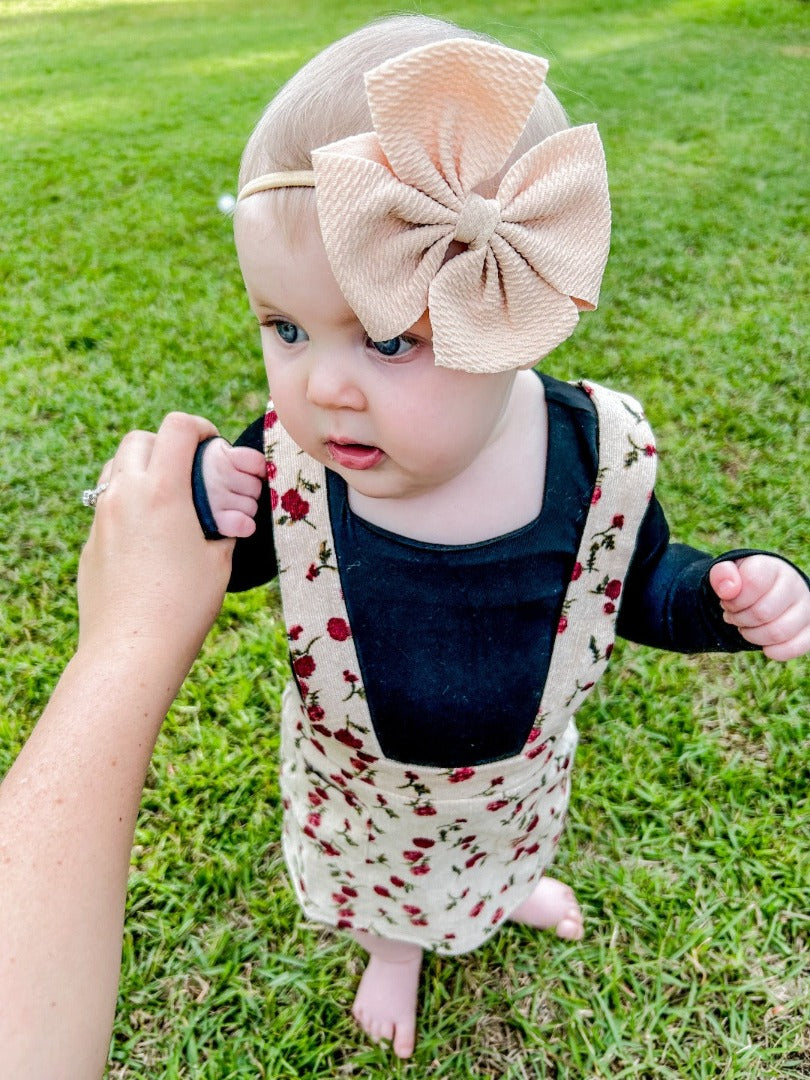 Girls' Corduroy Suspender Skirt in light pink with red flower patterns.