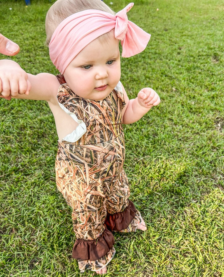 Girls' Girls Hunt Too Overall Set featuring a brown long-sleeved shirt with cuff ruffles, paired with camo-print overalls. The overalls are adorned with ruffles at the edges and cuffs, combining brown and camo patterns.