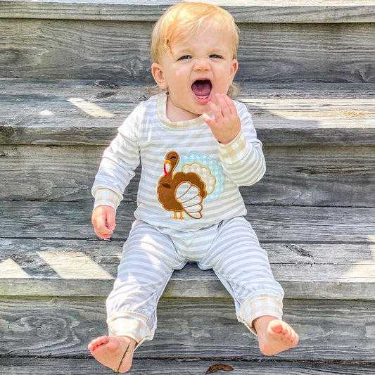 Boys' Mr. Gobble Outfit: A jumper-style garment with white and light grey stripes, showcasing a big turkey on the front. The cuffs are adorned with a light brown checkered pattern.