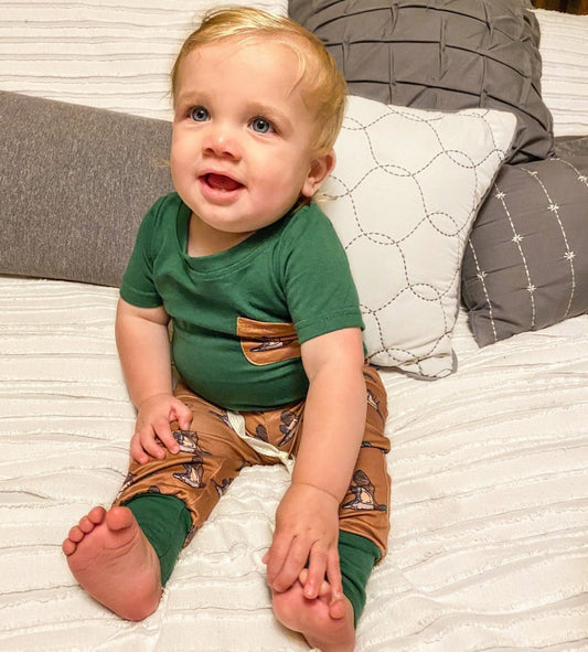 Boys' Duck Duck Boom Lounge Set featuring a dark green shirt with a brown pocket adorned with a duck motif, complemented by brown drawstring pants with duck patterns and dark green cuffs.